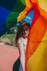 Young woman covering by a rainbow flag