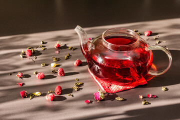 Sunny morning breakfast. Sweet raspberry green tea in glass kettle with dry fruits, flowers and...