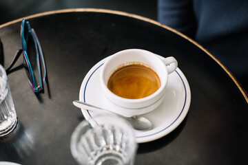 A cup of delicious fresh morning espresso coffee with a beautiful crema on the table, close up view 