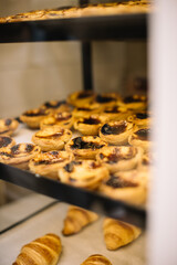 Delicious fresh Pastel de Nata and croissants in the Portuguese bakery window, vertical photo
