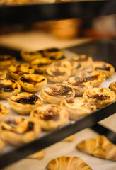 Delicious fresh Pastel de Nata and croissants in the Portuguese bakery window, vertical photo