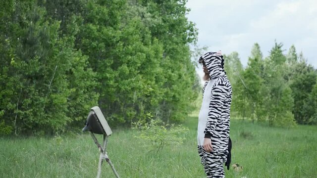 a man in a Zebra costume,with a painted face, bright emotion, jumping in the forest, slow shooting, Sunny weather, funny moment, good mood