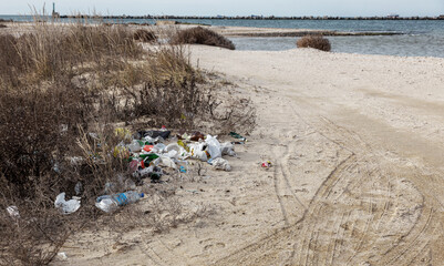 Poured garbage on Sea coast is left by tourists and vacationers. Dirty sea sandy shore of  Sea. Environmental pollution. Environmental problem has negative impact. Empty used dirty plastic bottles