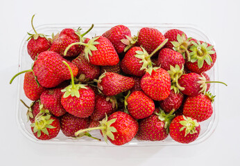 plastic tray with strawberries on a white background. View from above. Ukrainian strawberry. Close-up.