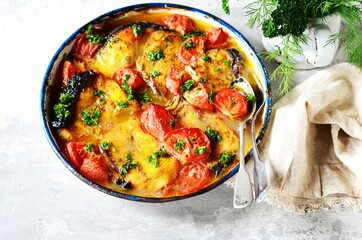 Baked fish (shark) with tomatoes and spices in a baking dish on a gray background, still life