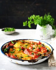 Baked fish (shark) with tomatoes and spices in a baking dish on a gray background, still life