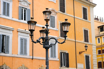 Fototapeta na wymiar Vintage street light in the Rome square near the ginger building with shutters 