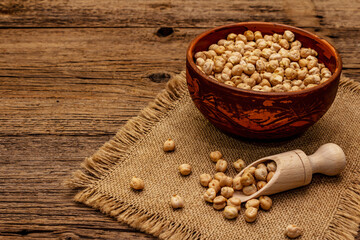 Dry chickpea in ceramic bowl on old wooden boards background. Traditional ingredient for cooking hummus