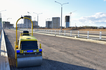 Paving roller machine during road work. Mini road roller at construction site for paving works. Screeding the sand for road concreting. Asphalt pavement is layered over concrete pavement