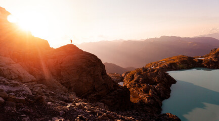 Hiker or alpinist at the top of a mountain. A success of mountaineer reaching the summit. Outdoor...