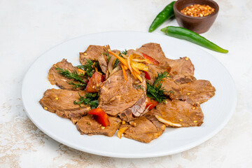 Beef salad with vegetables on a white, round plate