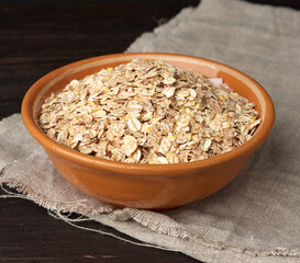 raw oatmeal in a brown ceramic plate on a wooden table