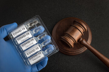Ampoules with vaccine for coronavirus and judges gavel. Laws and decisions against covid-19