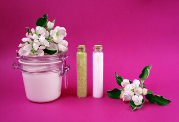 Hand made body cream or lotion, salt and sugar on the pink background. Apple blossoms. Natural cosmetics. Small business. Copy space. Glass jar