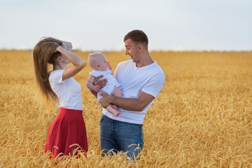 Young couple with child in wheat field. Mom dad and baby having fun in countryside
