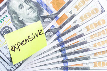 Yellow stick note on an USD 100 dollars money fan background. The inscription 