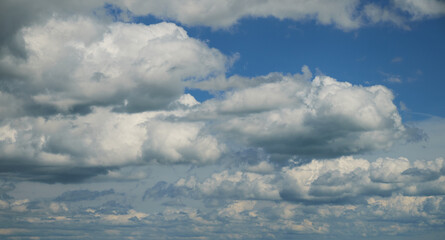 Dramatic blue summer sky with white puffy sunny clouds.