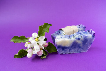 Hand made soaps on the purple background. White flowers on the natural cosmetic. Small business