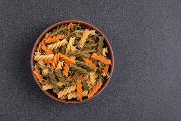Pasta Fusilli in bowl on gray background. Raw Italian pasta. Top view. Copy space. Template. Mockup