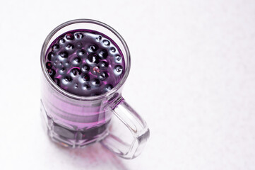 Frozen fruit blueberries in a transparent glass on a white background