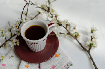 a cup of coffee with flowering tree branches