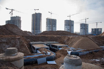 Laying heating pipes in trench at construction site. Installing concrete sewer wells and underground storm systems of sanitary water main. Cold and hot water heating system of the apartments in house