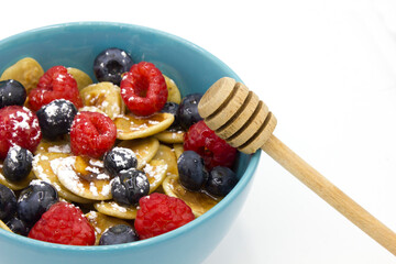 close up Stack of american blueberry Pancakes with berries, with honey spoon and pouring honey in blue bowl on white background.