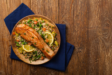 Asian dish. Fried salmon with rice and vegetables. Sprinkled with sesame seeds.