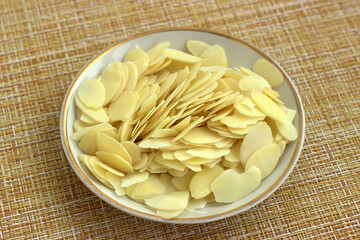 A small plate with almond shavings close-up on an obliquely rotated napkin. Muesli Ingredients