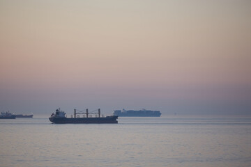 Obraz premium Commercial cargo ships on North Sea crossing in evening dusk light approaching night