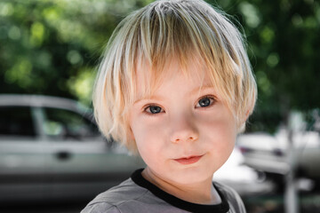 close-up portrait of a little boy with blue eyes on a blurred background in the street