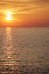 Commercial cargo ships sailing across North Sea in golden sunset light