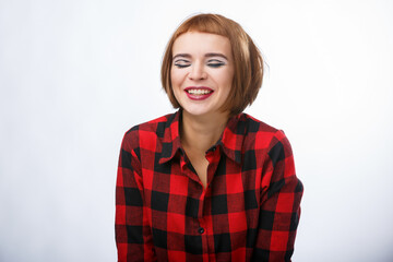 Happy emotions. Lady with red hair smiles with closed eyes. Girl in checkered shirt on white background.