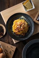 Delicious pasta carbonara on black plate.