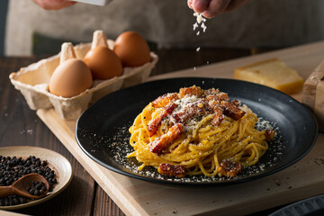Delicious pasta carbonara on black plate.