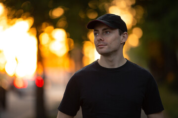 Stylish man in t-shirt and cap walks in a summer park