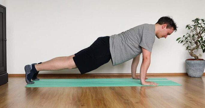 young man doing her workout at home - pushup exercise