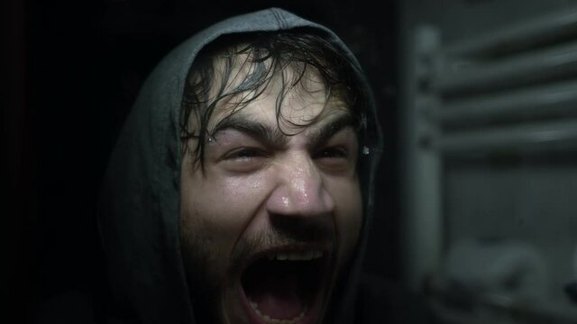 Sweaty and tired Young street fighter or boxer yelling in front of mirror. He's motivating himself.