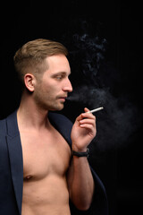 Sports guy in a jacket smokes a cigarette on a black background