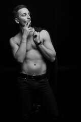 Fototapeta premium Sports guy in a jacket smokes a cigarette on a black background