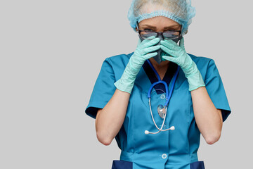 female doctor with stethoscope wearing protective mask and latex gloves over light grey background