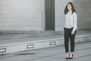 Elegant businesswoman in white shirt and black pants walking to a meeting with a client