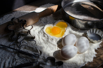 egg is broken into flour in the shape of a heart. cookie making process
