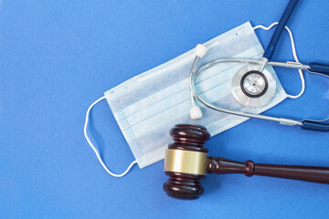 shot brown gavel, medical stethoscope and mask on a blue background. the concept of medical error.. free copy space for text. close up top view