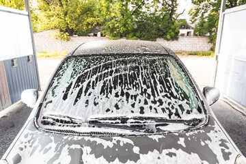 .the car is covered with foam at a self-service car wash. Close-up of a windshield
