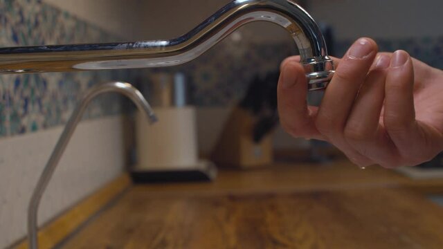 Close up male hand screwing filter on a kitchen faucet. Reparing of plumbing. Housekeeping