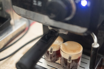 Two cups of espresso poured from a professional espresso machine