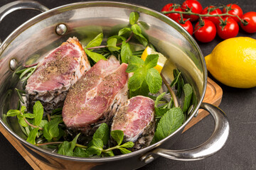 Fresh river fish with mint in a pan. Lemon and tomatoes on the table.