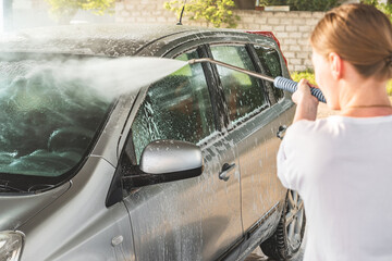 girl washes her car in a self-service car wash. watering the windshield