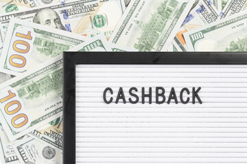 CASHBACK word on white letter board close up with lots of hundred dollar notes background. Copy space. Loyalty program for customers